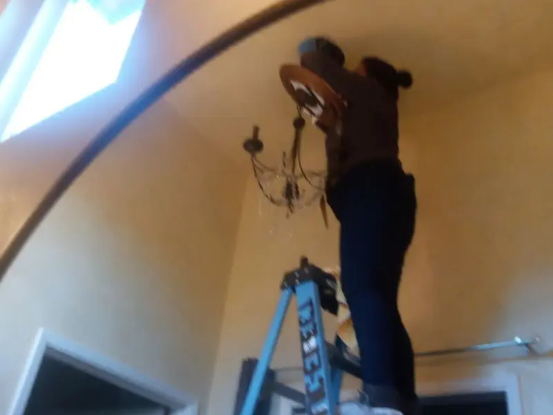 Electrician installing a chandelier in a Constantine residence